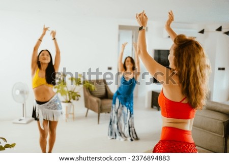 Picture of a group of female friends  performing Belly Dance in beautiful costumes. with fun at their homes, woman dance, Belly dancer in legging and hip scarf dancing. Royalty-Free Stock Photo #2376894883