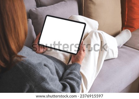 Mockup image of a woman holding digital tablet with blank desktop screen while lying on a sofa at home Royalty-Free Stock Photo #2376915597