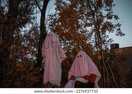 two sheet ghosts in front of trees Royalty-Free Stock Photo #2376937733