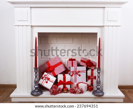 Fireplace with Christmas boxes and candles on wooden floor