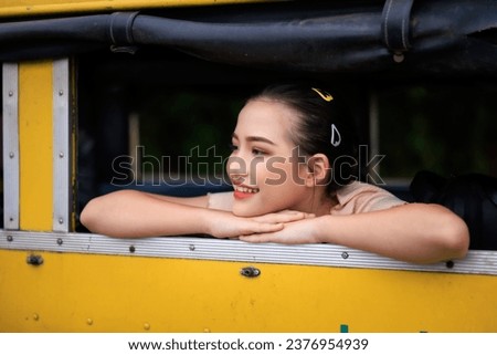 close up and selective focus portrait of young asian girl smiling at window yellow minibus,