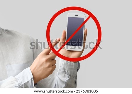 Businesswoman holding mobile phone with stop sign on light background. No Interruptions Day