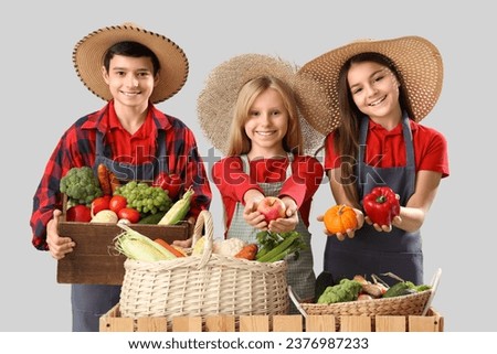 Little farmers with fresh food at counter on light background