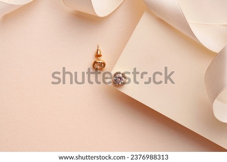 Golden earrings on paper background studio shot Royalty-Free Stock Photo #2376988313