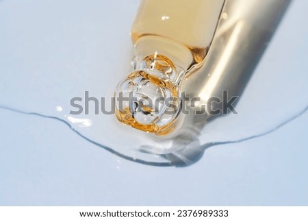 Bottle pipette dropper close up and Liquid yellow-orange retinol or vitamin c gel or serum on a blue background Royalty-Free Stock Photo #2376989333