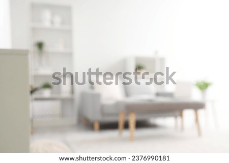 Blurred view of light living room with sofa and soft bench Royalty-Free Stock Photo #2376990181
