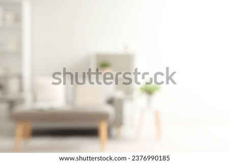 Blurred view of light living room with sofa and soft bench