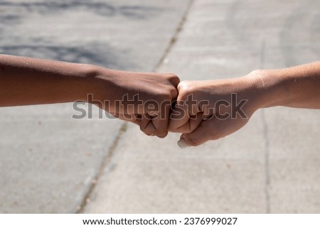 Hands of different ethnicities, African and European, bumping fist to fist in a concept of friendship or camaraderie Royalty-Free Stock Photo #2376999027