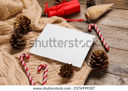 Beautiful Christmas composition with blank card, sweater and decor on wooden background