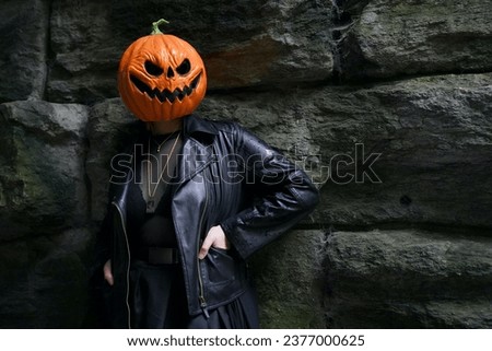 An adult model in a pumpkin head mask poses for a portrait in front of a brick background under Glen Span Arch in Central Park