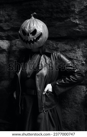 An adult model in a pumpkin head mask poses for a portrait in front of a brick background under Glen Span Arch in Central Park in black and white