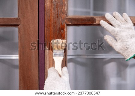 Worker use brush apply wood preserver after sandling the old surface of wooden window Royalty-Free Stock Photo #2377008547