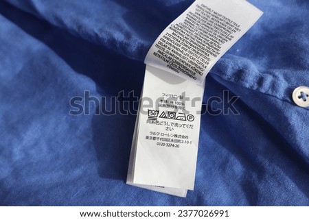 Clothing label in different languages on blue garment, closeup