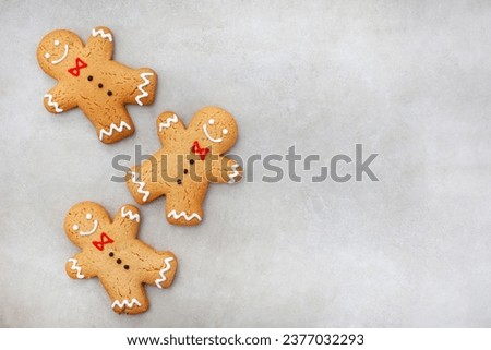 Three gingerbread men on mottled grey surface Royalty-Free Stock Photo #2377032293