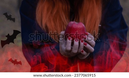 Halloween, red-haired Witch with an apple in a dark forest. A girl in the smoke performs witchcraft.
