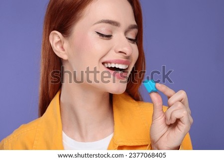 Beautiful woman with bubble gum on purple background