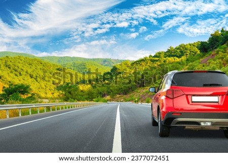Road landscape with red car in beautiful nature. car drive on highway scenery. View of travel by car on mountain road on sunny day. summer vacation trip by car on highway by the green mountain.