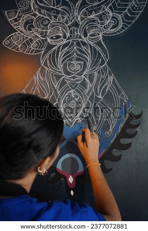 Woman drawing a picture on the wall with a brush. Beautiful model woman making artistic drawing on the wall