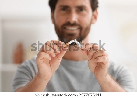Stop smoking concept. Man breaking cigarette on blurred background, selective focus Royalty-Free Stock Photo #2377075211