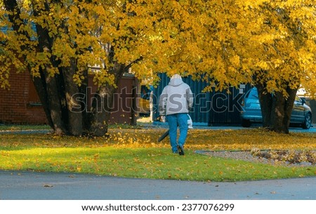 The janitor blows autumn leaves in the park. Communal services in city parks