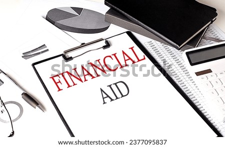 FINANCIAL AID text on paper clipboard with chart and notebook on a withe background