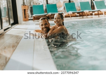 Handsome young couple relaxing in the indoor swimming pool Royalty-Free Stock Photo #2377096347