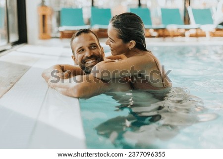 Handsome young couple relaxing in the indoor swimming pool Royalty-Free Stock Photo #2377096355