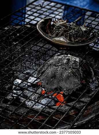 a fish on a grill with a bowl of fire.