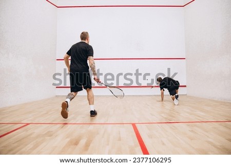 Portrait of two young sportive men training, playing squash game in special sport studio. Energetic play. Concept of active life, team game, energy, sport, competition. Copy space for ad Royalty-Free Stock Photo #2377106295