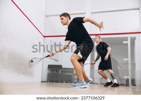 Side view portrait of two young boys in motion, playing squash isolated over sport studio background. Concept of active life, team game, energy, sport, competition. Copy space for ad Royalty-Free Stock Photo #2377106329