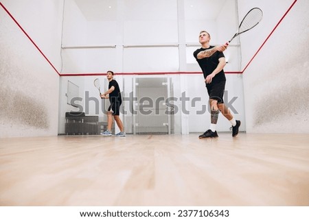 Portrait of two young sportive boys training together, playing squash isolated over sport studio background. Concept of active life, team game, energy, sport, competition. Copy space for ad Royalty-Free Stock Photo #2377106343