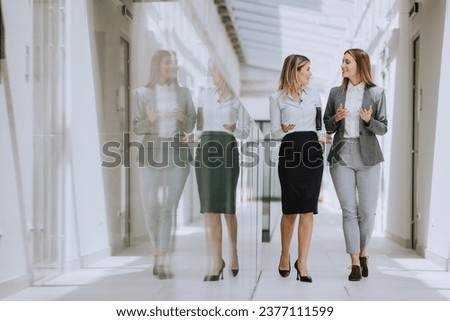 Two pretty young business women walking and discussing in the office hallway Royalty-Free Stock Photo #2377111599