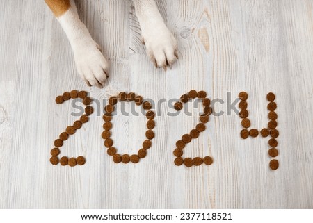 2024 are lined with pellets of dry food and dog paws. Happy New Year 2024 with a pet. Royalty-Free Stock Photo #2377118521