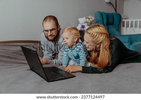 Parents with kid with computer at home on the bed. High quality photo