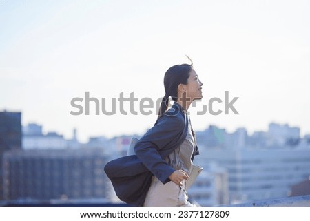 A Japanese man wearing a jacket running in a business district Royalty-Free Stock Photo #2377127809