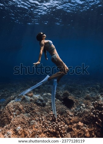 Woman freediver with fins glides over corals. Free diving in tropical blue ocean Royalty-Free Stock Photo #2377128119