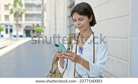 Young beautiful hispanic woman tourist using smartphone at street