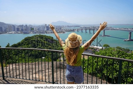 Happy tourist girl visiting Brazil. Beautiful young woman with raised arms enjoying view panorama of Vitoria the capital of Espirito Santo state in Brazil. Royalty-Free Stock Photo #2377163335