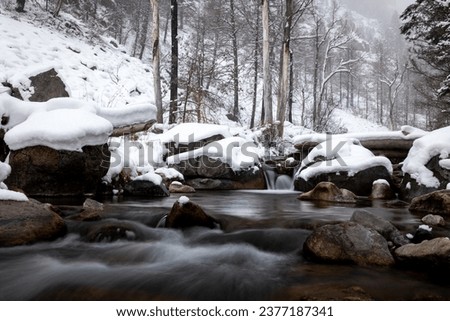 Flowing winter stream with snow Royalty-Free Stock Photo #2377187341