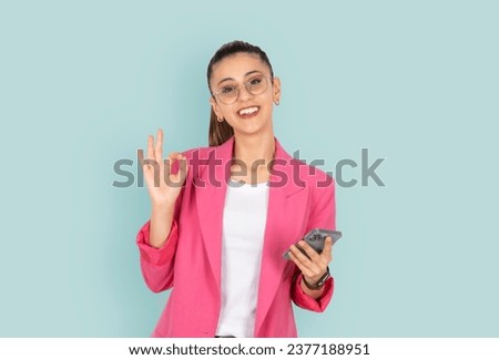 Business woman show ok gesture,  young caucasian happy business woman show ok gesture. Office worker employee hold mobile cell phone over blue studio background. People lifestyle concept idea.
