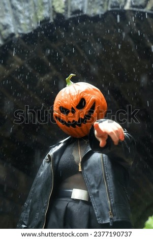 An adult model wearing a pumpkin mask poses for a portrait by pointing to the camera in front of Glen Span Arch in Central Park 