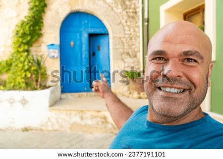 Smiling man takes a selfiewith a beautiful blue door on background.