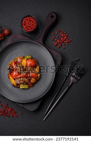 Warm salad with veal, tomatoes, peppers, zucchini, sesame, salt, spices and herbs on a dark concrete background Royalty-Free Stock Photo #2377192141