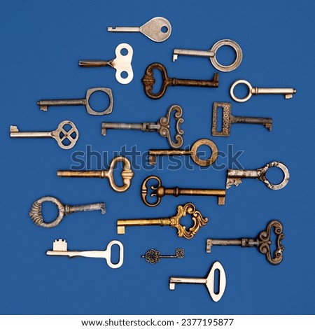 Top view photo of keys. Decorative, vintage, antique keys for clocks and caskets and doors with unique shapes and designs over blue background. Concept of history, home, real estate