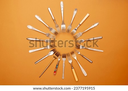 Cutlery. Pop art style. Flat lay of variety of stainless steel, antique silverware and gold forks arranged in circle over orange studio background. History, home, real estate, detail, classic concept Royalty-Free Stock Photo #2377195915