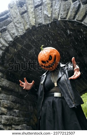A model wearing a pumpkin head mask poses for a portrait for a spooky portrait in front of Glen Span Arch in Central Park on a rainy day