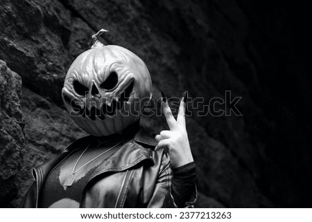 An adult model wearing a pumpkin head mask makes a peace sign while posing for a portrait under Glen Span Arch in Central Park in black and white