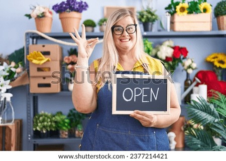 Caucasian plus size woman working at florist holding open sign doing ok sign with fingers, smiling friendly gesturing excellent symbol 