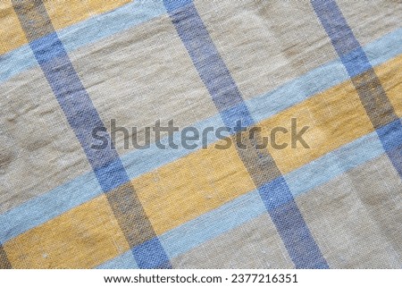 Linen towel with folds, rough fabric texture, weaving. Blue and yellow stripes on natural fabric. Background, texture.