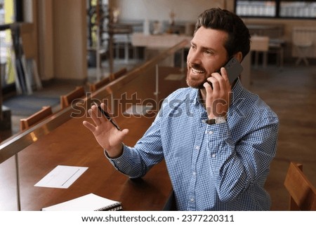 Handsome man talking on phone at table in cafe